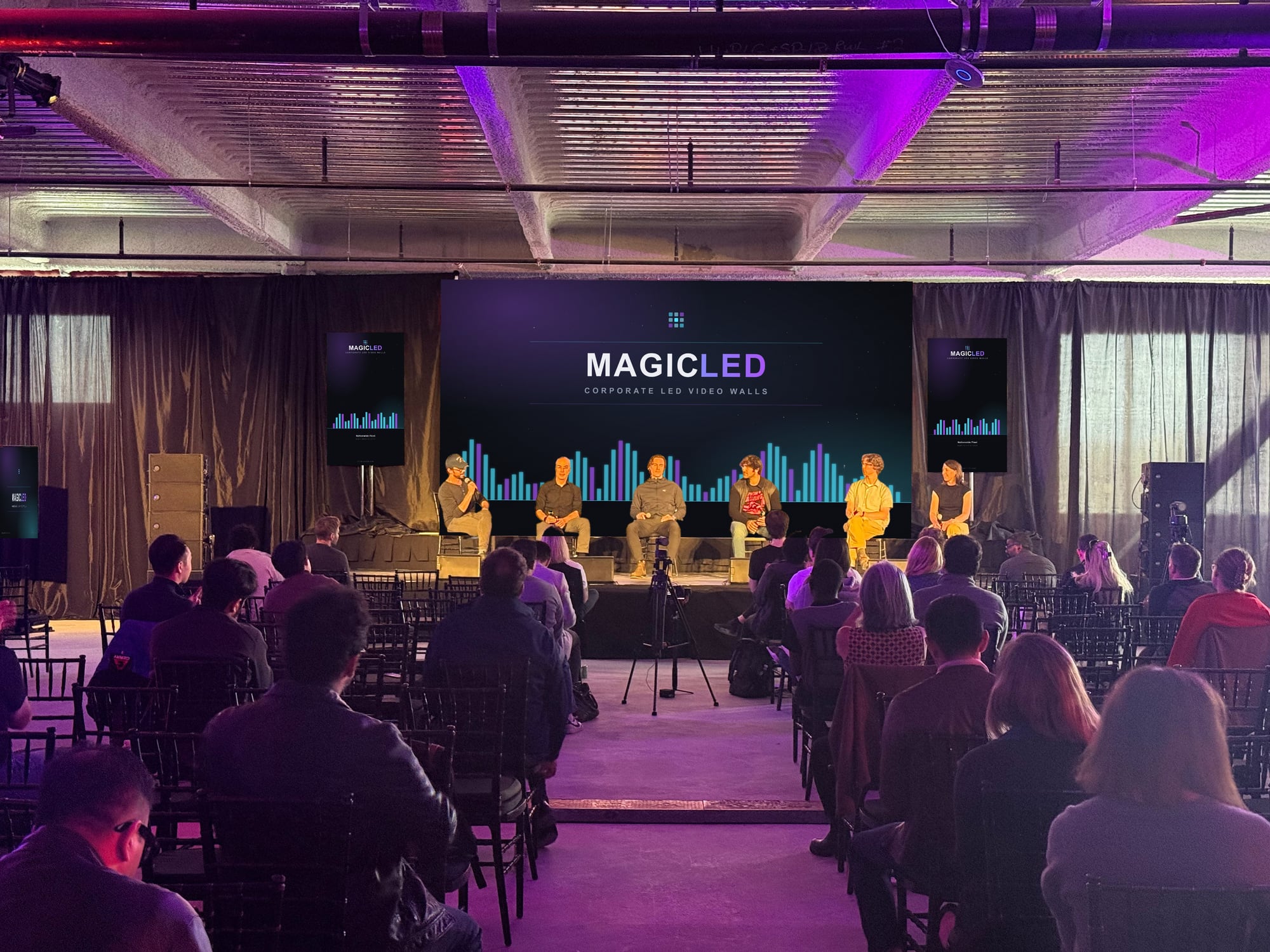 Seated audience watching a six-person panel in front of a Magic LED wall