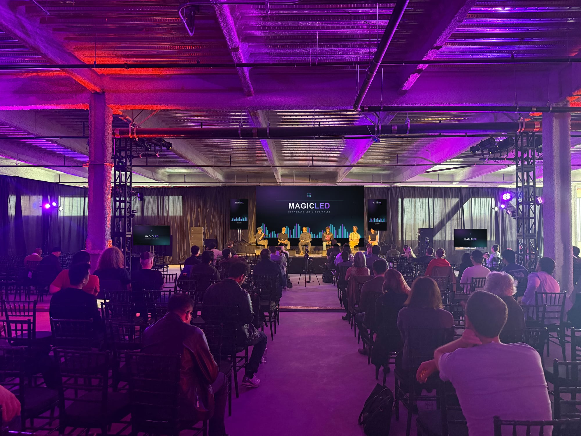 Wide view of a warehouse event space with a Magic LED wall at the far end